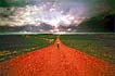 man walking alone on red dirt road